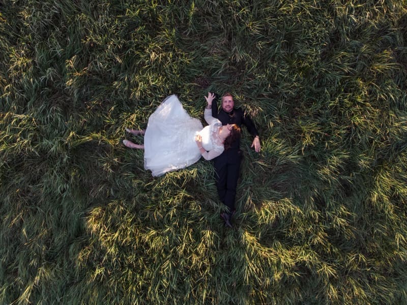 Aerial wedding portrait of newlyweds in a grassy field during the best season to get married.