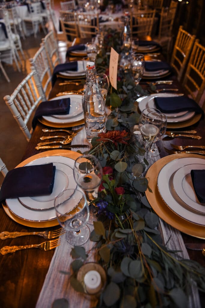 Barn Wedding Decor Ideas with greenery, candlelight, navy napkins, gold place settings, and elegant tablescape details.