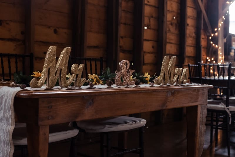 Barn Wedding Decor Ideas featuring a sweetheart table with gold Mr. and Mrs. signs and sunflowers.