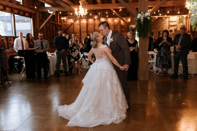 Bride and groom share their first dance inside the historic Barn on Hubbard as wedding guests watch, showing the indoor reception space couples can consider when making a list of questions to ask your wedding venue.
