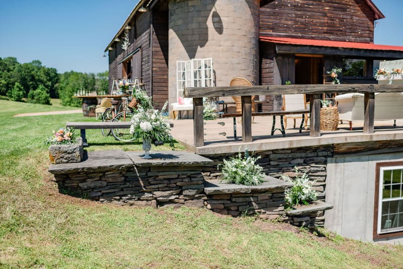 Outdoor patio at The Barn on Hubbard decorated with flowers, vintage furniture, and rustic details, showing one of the spaces couples may want to explore when deciding which questions to ask your wedding venue.